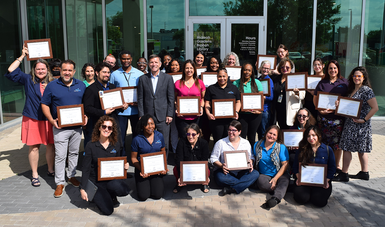 Group photo of library staff members holding framed certificates